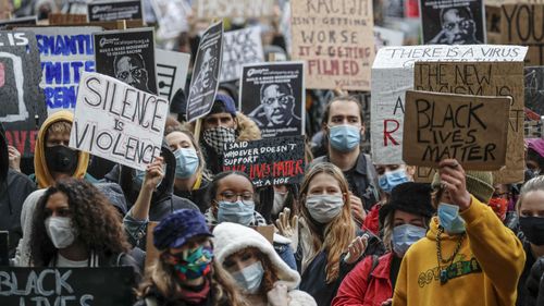 People hold placards during a Black Lives Matter rally in Parliament Square in London, Saturday, June 6, 2020