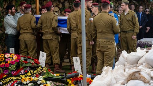 President of Israel Isaac "Bougie" Herzog (R) watches as the casket for 20-year-old Staff Sergeant Dvir Barzani is carried into the funeral led by IDF Chief Cantor Lt. Col. Shai Abramson at Har Herzel on November 21, 2023 in Jerusalem.