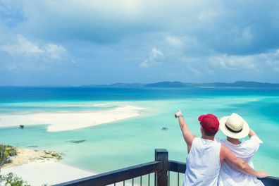 Couple looking at the view of Whitehaven beach.