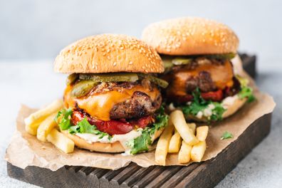 Delicious Juicy Cheeseburgers With Dill Pickles, Roasted Bell Pepper, Cheddar Cheese And Arugula Served With French Fries