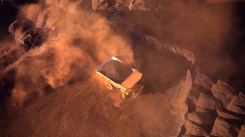 An iron ore truck stirs up the dirt as it drives through Eastern Ridge mine (Ethel Gorge) in Newman, Western Australia.