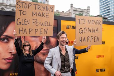 Glen Powell&#x27;s parents hold up signs behind him as they attend the special screening of Hitman in Austin, Texas on May 15.