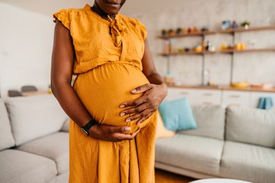 Pregnant woman holding her belly at home