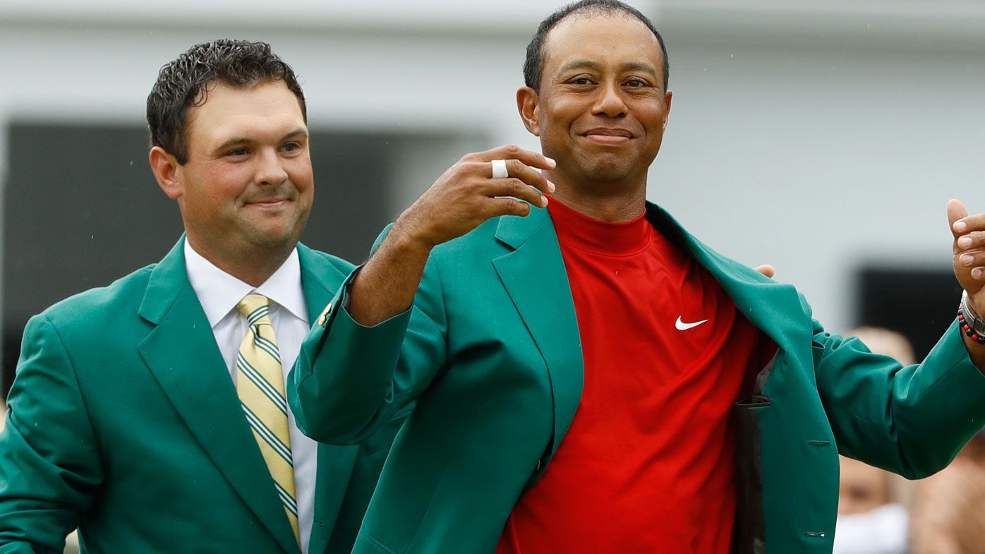 Patrick Reed, left, helps Tiger Woods with his green jacket after Woods won the 2019 Masters golf tournament