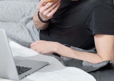 man using laptop eating pizza