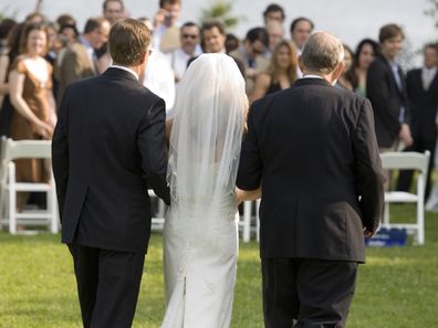 A bride being escorted by her father and grandfather at wedding.