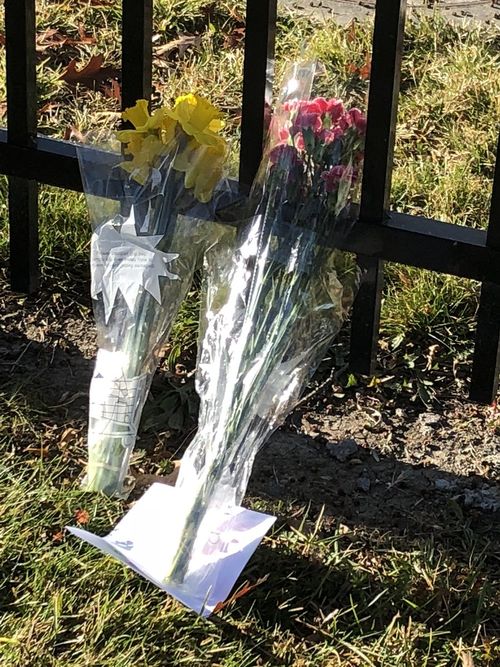 Flower tributes are left on the school fence. Picture: 9NEWS