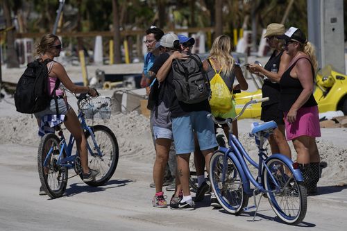 Des amis se voient pour la première fois depuis le passage de l'ouragan Ian s'arrêtent pour s'embrasser, alors qu'ils marchent et font du vélo sur l'île pour récupérer les effets personnels de tout ce qui reste de leurs maisons, à Fort Myers Beach, Floride, le vendredi 30 septembre 2022 