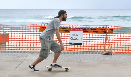 A man on a skateboard is seen going past the closed off Surfers Paradise beach on the Gold Coast, in April.