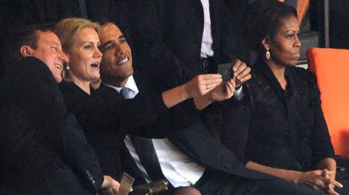 Barack Obama, David Cameron and Helle Thorning-Schmidt share a light moment among a sombre crowd dressed in black.  