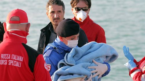 A Red Cross worker carries a baby rescued from the stricken ship. (AAP)