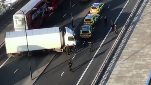 In this image made from video provided by Luke Poulton, armed police surround a truck parked across lanes of traffic on London Bridge, following an incident in central London, Friday, Nov. 29, 2019