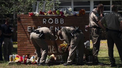 Two Texas Troopers light a candle at Robb Elementary School in Uvalde, Texas.