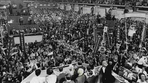 Prior to 1968, the presidential nominees would be decided by a vote at the convention. In this 1964 photo, President Lyndon Johnson waves in the foreground after accepting the nomination.