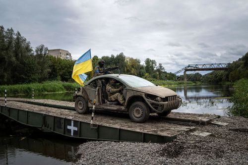 Ukrainian paratroopers drive with a Ukrainian flag on a pontoon bridge across Siverskiy-Donets river