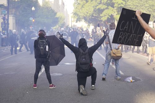 Demonstrators kneel in front of a line of police officers during a protest for the death of George Floyd, near the White House in Washington