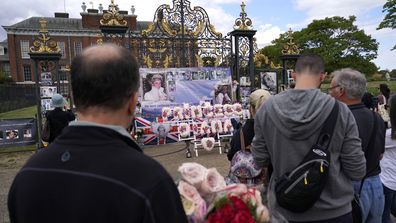 People line up to leave floral arrangements in remembrance of Princess Diana outside the gates of Kensington Palace, in London, Wednesday, August 31, 2022.  