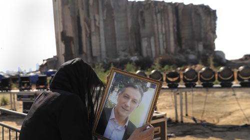 A relative of a victim who was killed in the massive blast last year at the Beirut port reacts and holds his portrait.