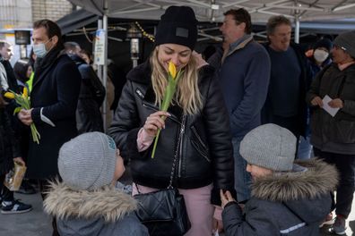 BUDAPEST, HUNGARY - MARCH 08: Ukrainian woman and children hold a flower at the Western Railway Station on International Women's Day as they flee Ukraine on March 8, 2022 in Budapest, Hungary. More than 2 million refugees have fled Ukraine since the start of Russia's military offensive, according to the UN. Hungary, one of Ukraine's neighbouring countries, has welcomed more than 144,000 refugees fleeing Ukraine after Russia began a large-scale attack on Ukraine on February 24. (Photo by Janos Ku