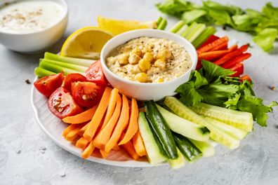 A plate with colorful healthy sliced vegetables and dips. 