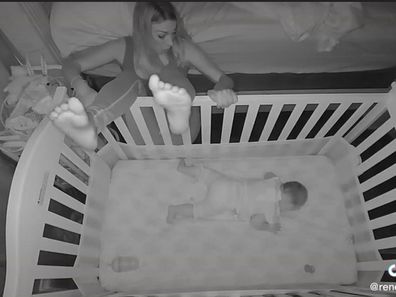 Baby monitor view of baby sleeping in cot and mum stuck between cot and bed.