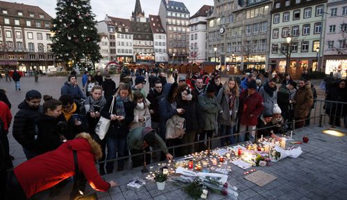 People light candles and leave signs and flowers on a place close to the Christmas Market where a shooting happened in Strasbourg, France