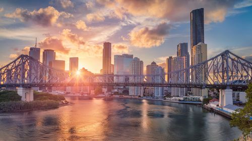 Cityscape image of Brisbane skyline, Australia with Story Bridge during dramatic sunset.