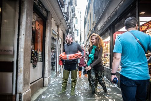 A pedestrian with a flotation ring around his middle laughs with a shop assistant.