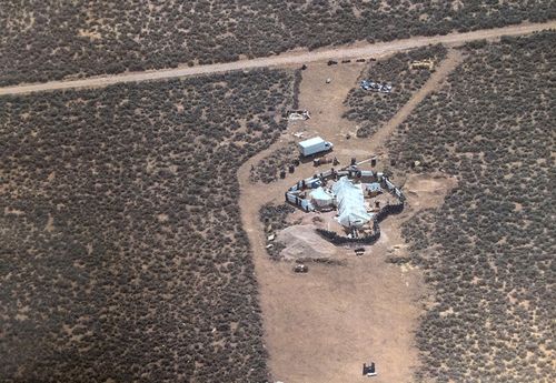 This Friday, Aug. 3, 2018, aerial photo released by Taos County Sheriff's Office shows a rural compound during an unsuccessful search for a missing 3-year-old boy in Amalia, N.M. Law enforcement officers searching the compound for the missing child didn't locate him but found 11 other children in filthy conditions and hardly any food, a sheriff said Saturday. The children ranging in age from 1 to 15 were removed from the compound and turned over to state child-welfare workers, Taos County Sheriff Jerry Hogrefe said.in Taos, N.M. (Taos County Sheriff's Office via AP)