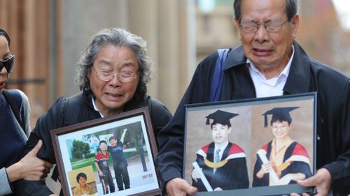 Granfather Yang Fei Lin  and grandmother Feng Qing Zhu leave court carrying photographs of their murdered family members. (AAP)