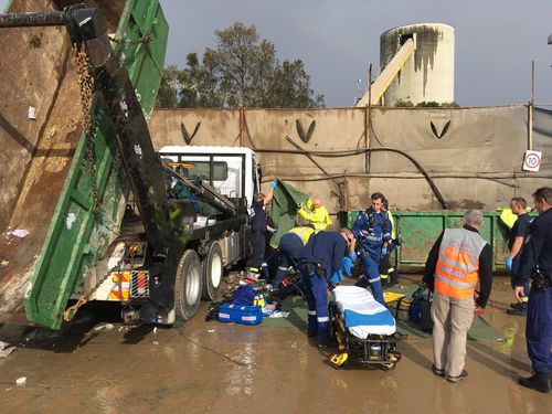 A man, aged in his 50s was freed after getting trapped by a garbage truck at a worksite in Sydney's west this morning.