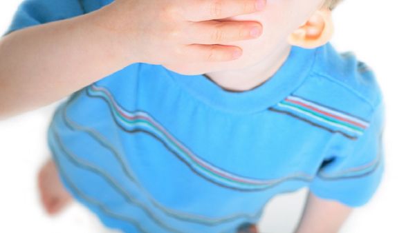 Toddler covers mouth with hand.