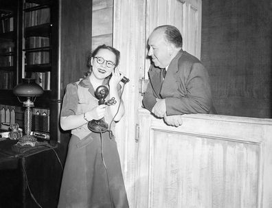 Alfred Hitchcock smiles as he watches his daughter Pat, 15, answer the phone during rehearsal for Violet, in which she plays the title role in 1944.