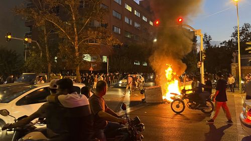 A police motorcycle and a trash bin are burning during a protest over the death of Mahsa Amini, a 22-year-old woman who had been detained by the nation's morality police, in downtown Tehran, Iran. This photo was taken by an individual not employed by the Associated Press on September 19, 2022 and obtained by the AP outside Iran.