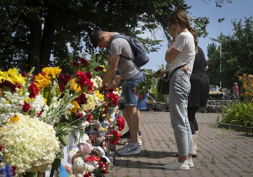 People lay flowers to pay the last respect to victims of the Russian rocket attack at a shopping center in Kremenchuk, Ukraine.