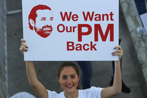 A Lebanese woman holds a placard supporting the outgoing Lebanese Prime Minister Saad Hariri to return from Saudi Arabia during the Beirut Marathon (AP Photo/Hassan Ammar)