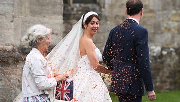 A woman throws orange confetti as former UK Chancellor George Osborne and Thea Rogers leave after their wedding at St Mary&#x27;s Church, in Bruton, England. 
