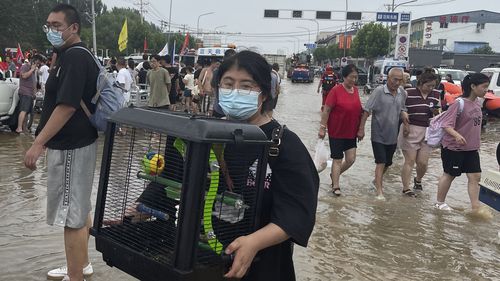 A woman evacuated from floods carries her pet bird in a cage in Zhuozhou in northern China's Hebei province, south of Beijing, Wednesday, Aug. 2, 2023. China's capital has recorded its heaviest rainfall in at least 140 years over the past few days. Among the hardest hit areas is Zhuozhou, a small city that borders Beijing's southwest. (AP Photo/Andy Wong)