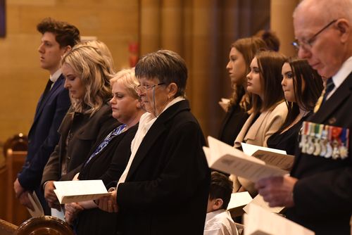  Pauline Johnson (centre) sits with her grandchildren during the State Funeral for her husband John Richard Johnson at St Mary's Cathedral. (AAP)