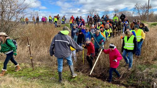 Volunteers cross a creek and barbed wire near Barron, Wisconsin, on their way to a ground search for 13-year-old Jayme Closs.