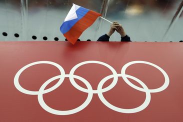 FILE - A Russian flag is held above the Olympic Rings at Adler Arena Skating Center during the Winter Olympics in Sochi, Russia on Feb. 18, 2014. (AP Photo/David J. Phillip, File)