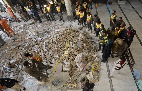 Rescue workers gather as they conduct an operation to clear the rubble and find the bodies at the site of Monday's suicide bombing, in Peshawar, Pakistan.
