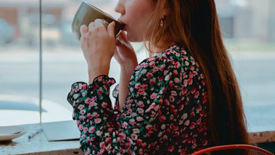 Stock photo of woman drinking coffee at a cafe.