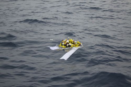 A wreath lays in the water at the scene of the crash site.