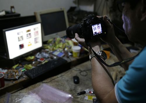 A Filipino member of the National Bureau of Investigation takes a picture of the computer of suspected child webcam cybersex operator, David Timothy Deakin, during a raid at his home in Mabalacat, Philippines.  (AAP)