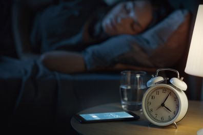 Woman in bed with her alarm going off early