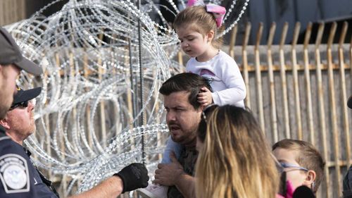 US Customs and Border officials speak to a caravan member at the San Ysidro port of entry between Tijuana and San Diego.