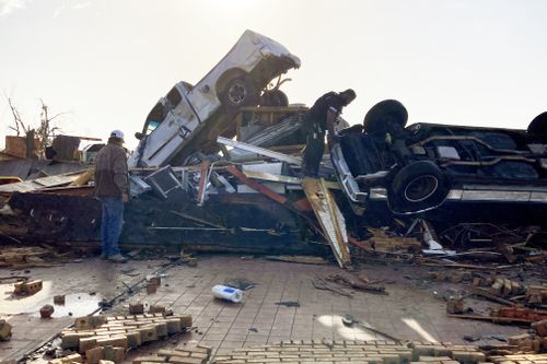 Law-enforcement officers climb through debris on a diner looking for survivors early Saturday, March 25, 2023 in Rolling Fork, Miss.  No one was found. 