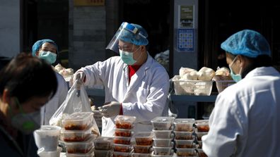 Workers wearing protective face masks pack food orders for customers outside a restaurant only offering take-out business to prevent people gathering following the coronavirus outbreak in Beijing.