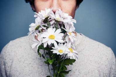 Young man is smelling a bouquet of fresh flowers